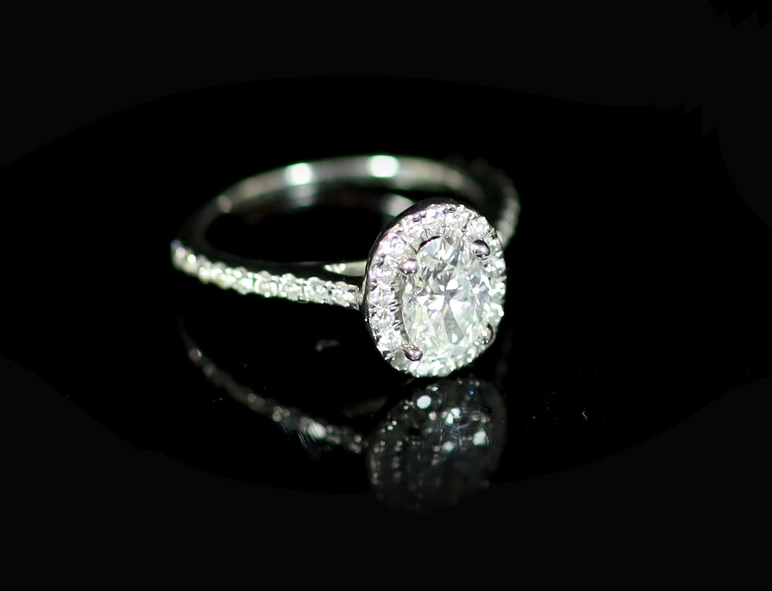 A Rox platinum and oval cut single stone diamond ring, with diamond set border and diamond set shoulders